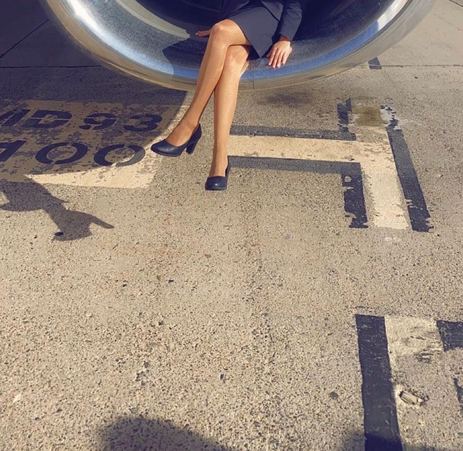 Crossed legs in navy heels sitting inside an aircraft engine cowling