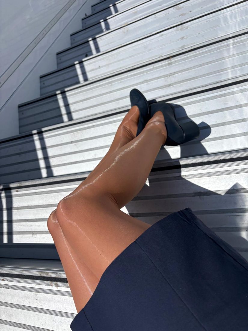 Legs in sheer tights and navy heels on aircraft stairs in sunlight