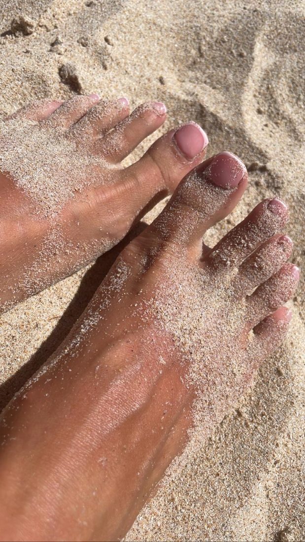Bare feet with pink nails in warm sand